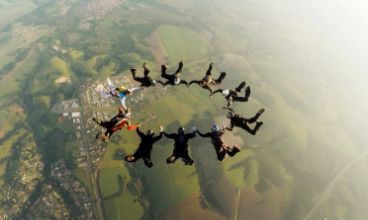 Ten people in a circular formation, flying in the air before their parachutes open.