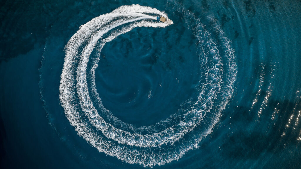 Aerial view of a speedboat cruising in a circle in deep blue water.