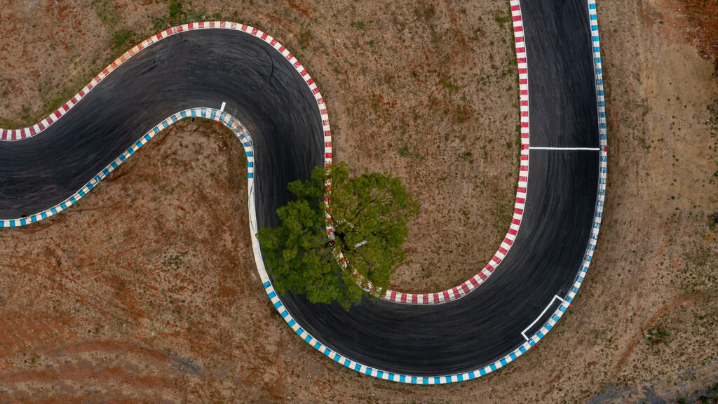 Aerial view of a part of an empty race track with a single tree in the middle.