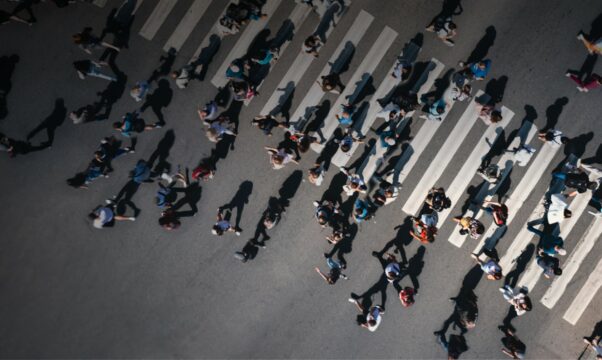 Aerial view of a mass of people walking on and beside a pedestrian crossing.
